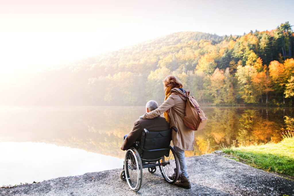 Senior with caregiver in wheelchair out enjoying nature.